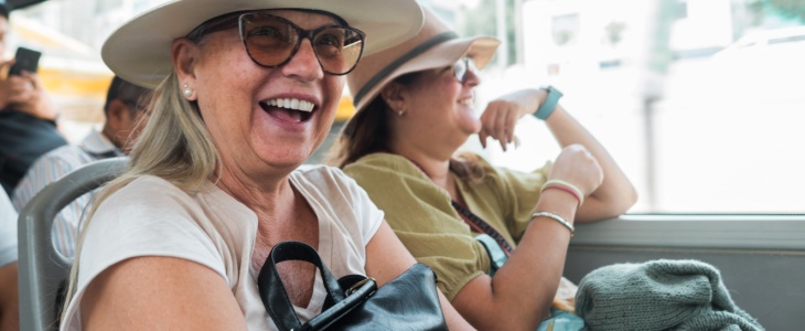 two women sit together happily on a tour bus