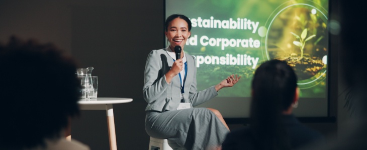 a woman on stage presents to a crowd at a conference