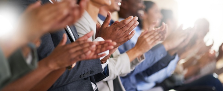 A group of attendees clap after a panel discussion
